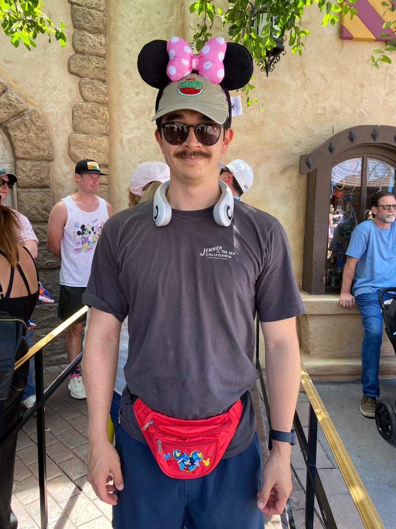 Scott at Disneyland wearing Minnie Mouse ears over a cap and a red fanny pack