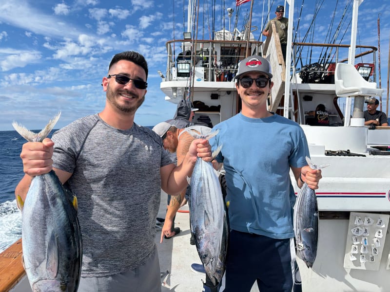 Scott and a friend on a sport fishing boat, each holding two tuna