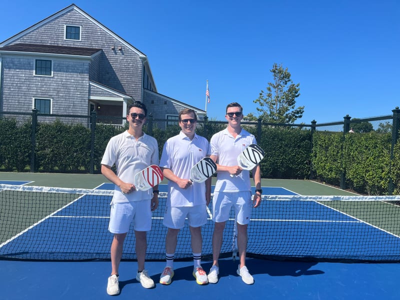 Scott and two friends in tennis whites holding paddles on a pickleball court
