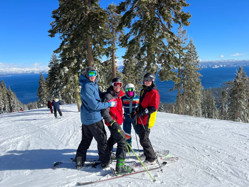 Scott and three friends in ski gear at the top of a run, Lake Tahoe far below